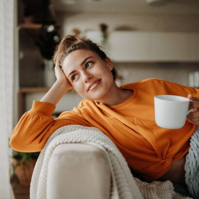 Jeune femme se reposant sur le canapé avec une tasse de thé.